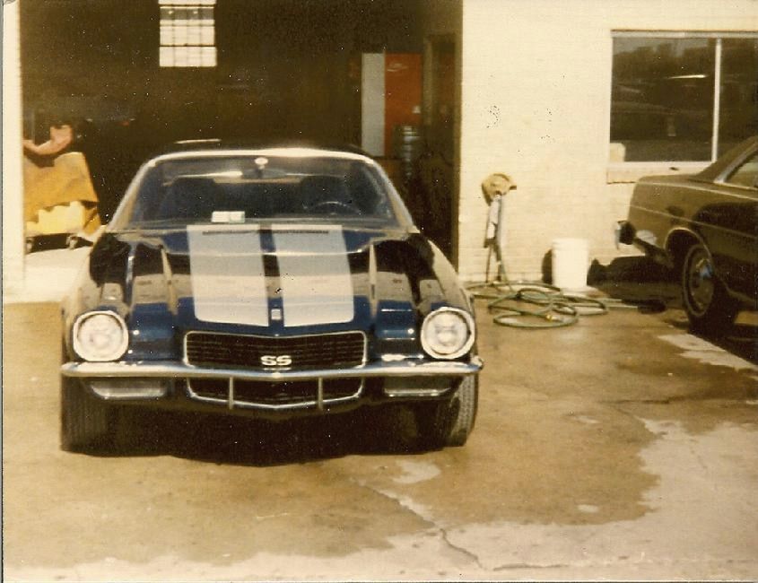An old print of a Camaro SS parked in the shop bay