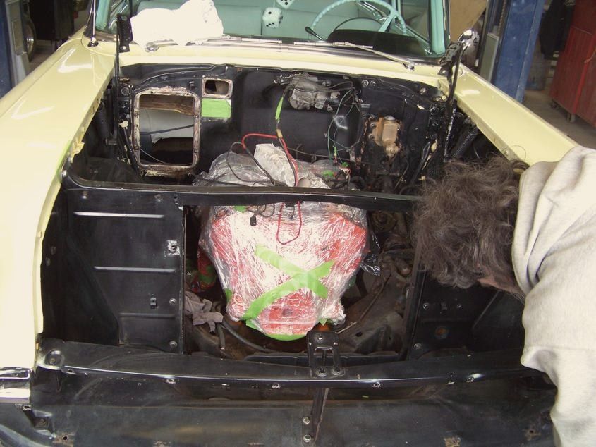 A 1957 Chevrolet in the shop with its engine bay being rewired