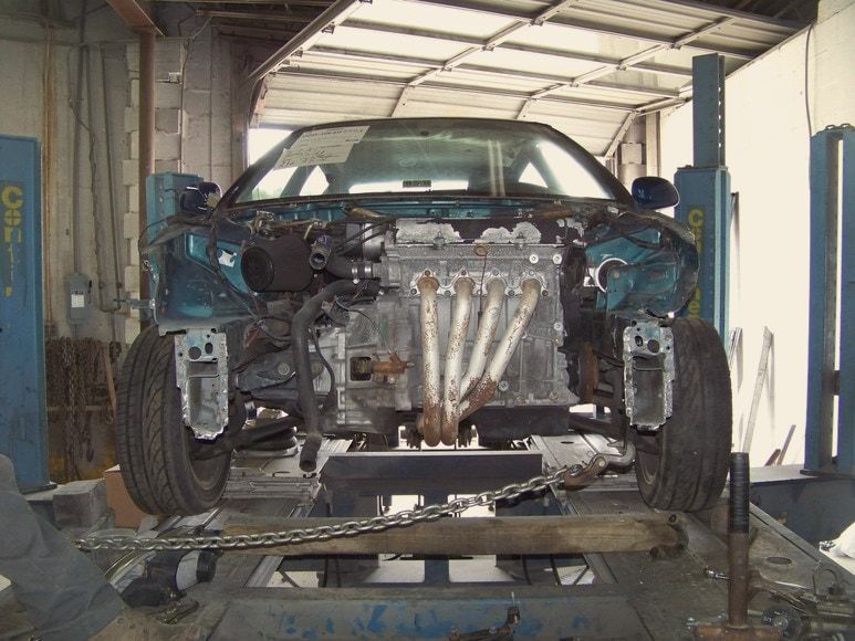 A wrecked Honda Civic chained to the frame rack inside GAC Automotive Center