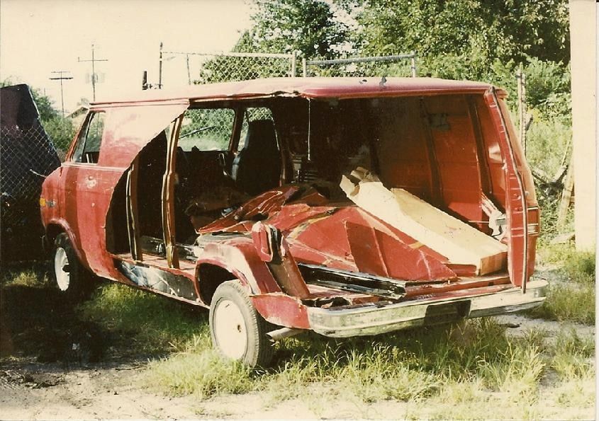 An old photo of a red van with its side torn open
