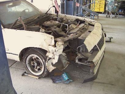 A white 1984 Monte Carlo SS with front-end damage, hood open