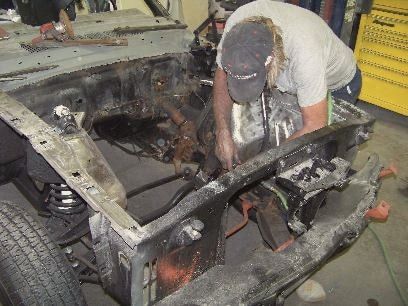 Bare-metal cowl and engine bay of a 1965 Mustang after rust removal