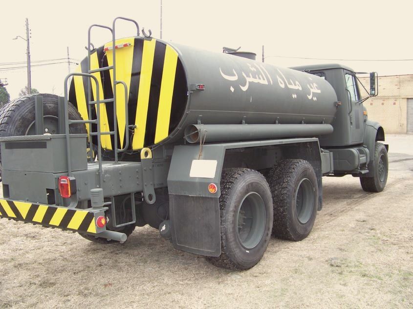 A military water tanker truck repainted green with yellow and black hazard stripes