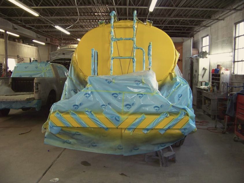 A military water tanker masked off for paint inside the shop