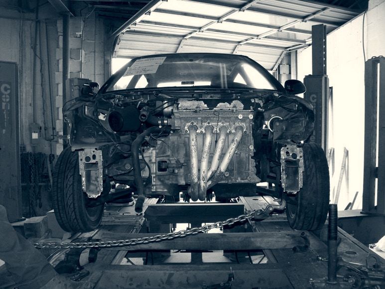 A wrecked Honda Civic chained to the frame rack for straightening
